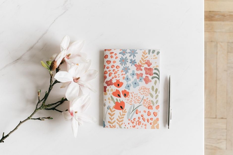 A floral notebook and pen on a light table